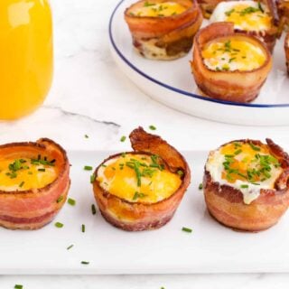 eggs in muffin pan with bacon on a white tray in a single row