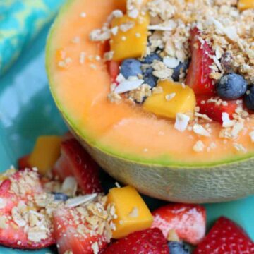 yogurt cantaloupe bowl recipe garnished with granola and fruit on a blue plate