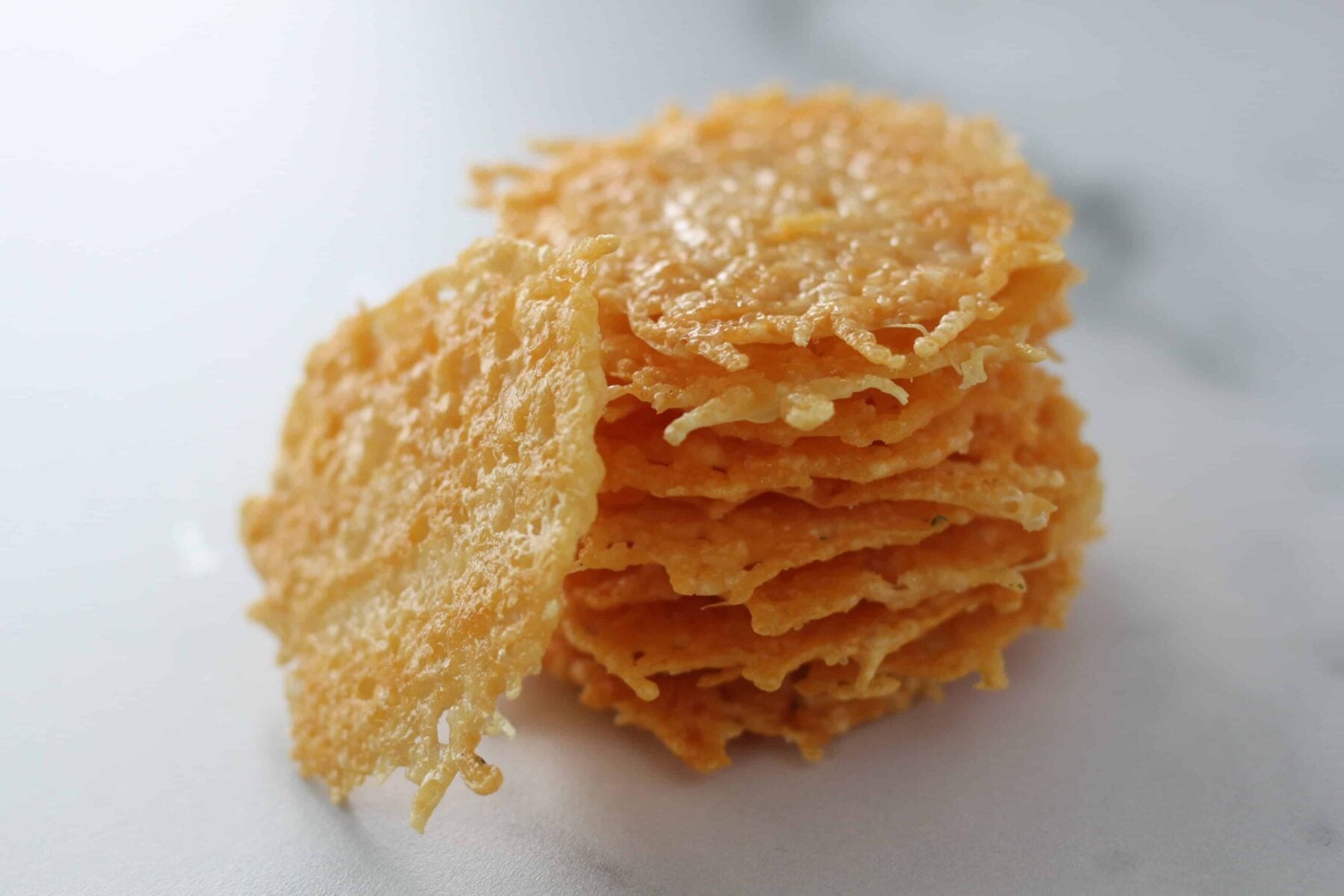 parmesan cheese crisps stacked up on a marble cutting board
