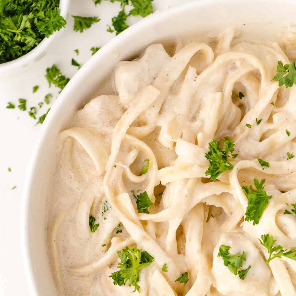 easy alfredo sauce in a white bowl topped with parsley