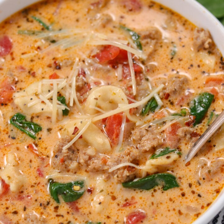 tortellini soup with sausage in a bowl sprinkled with parm