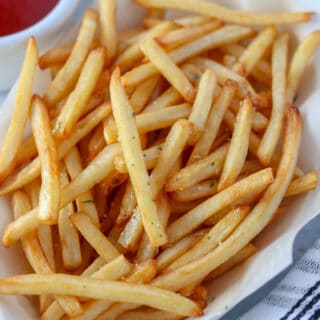 air fried frozen shoestring fries crispy and cooked in a white dish with a side of sauce