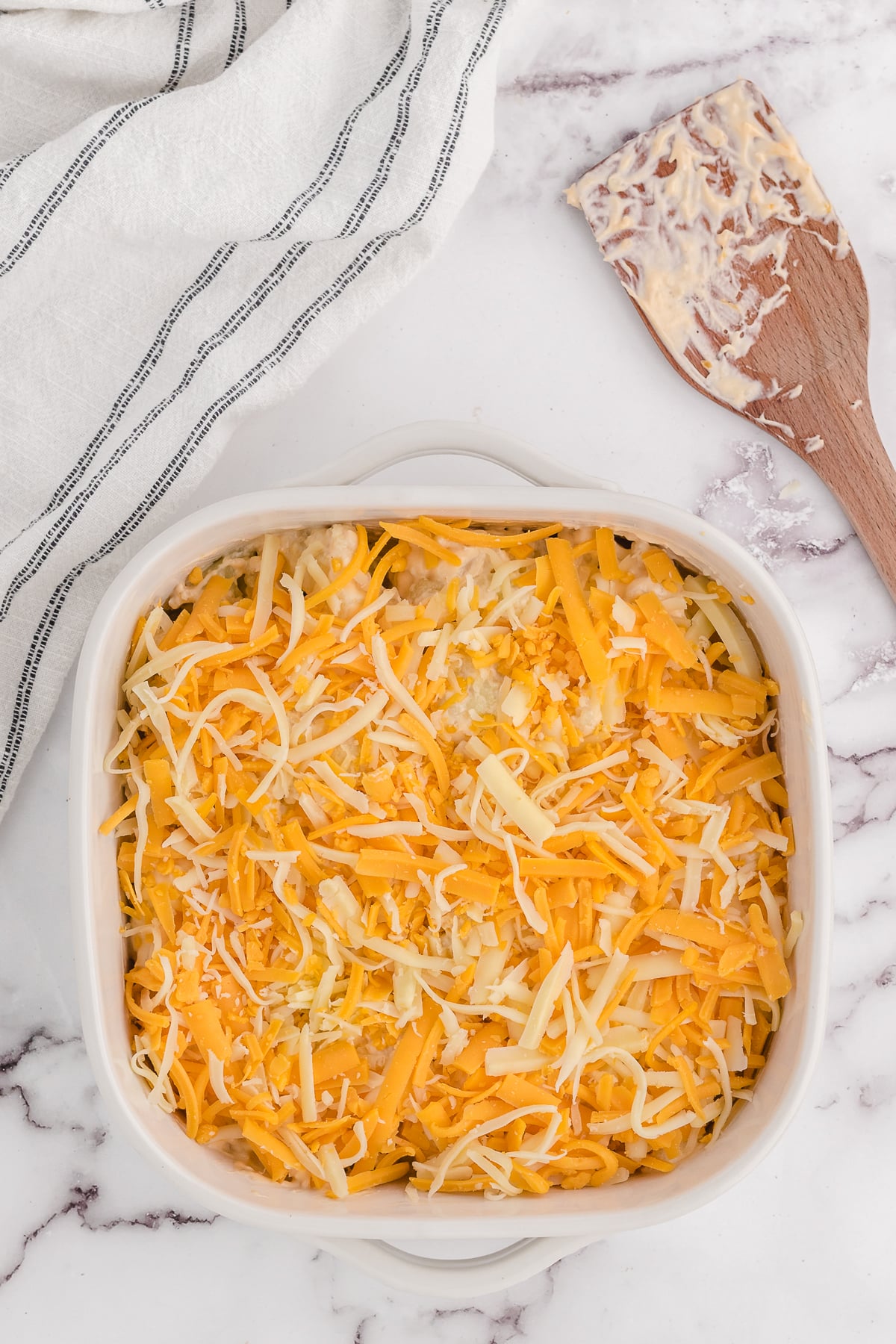 sprinkling the shredded cheese on top of the keto mac and cheese before baking