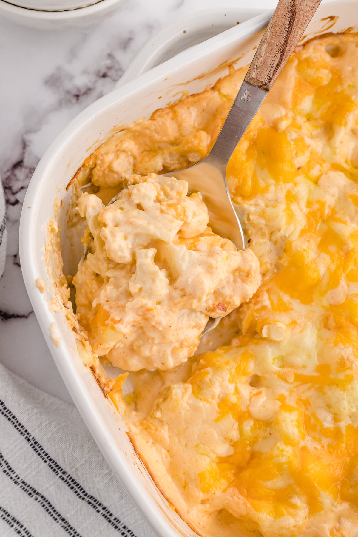 low carb cauliflower mac and cheese with a spoon scooped out of the casserole dish