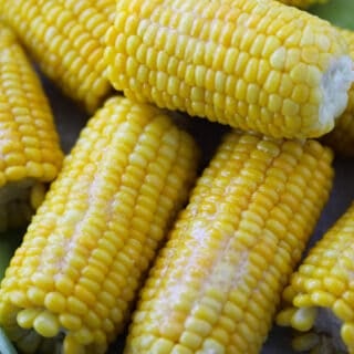 how to cook frozen corn on the cob is the same as fresh corn. Showing finished corn with butter up close after cooking.