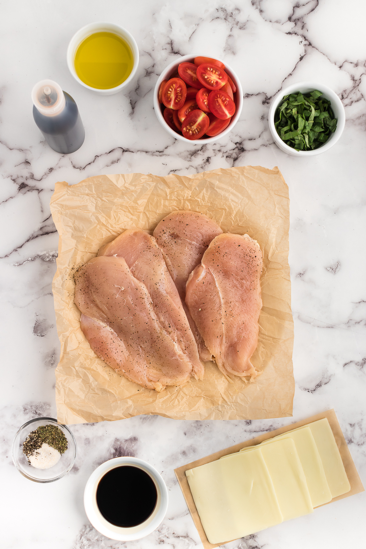ingredients for chicken caprese bake on a white marble counter top