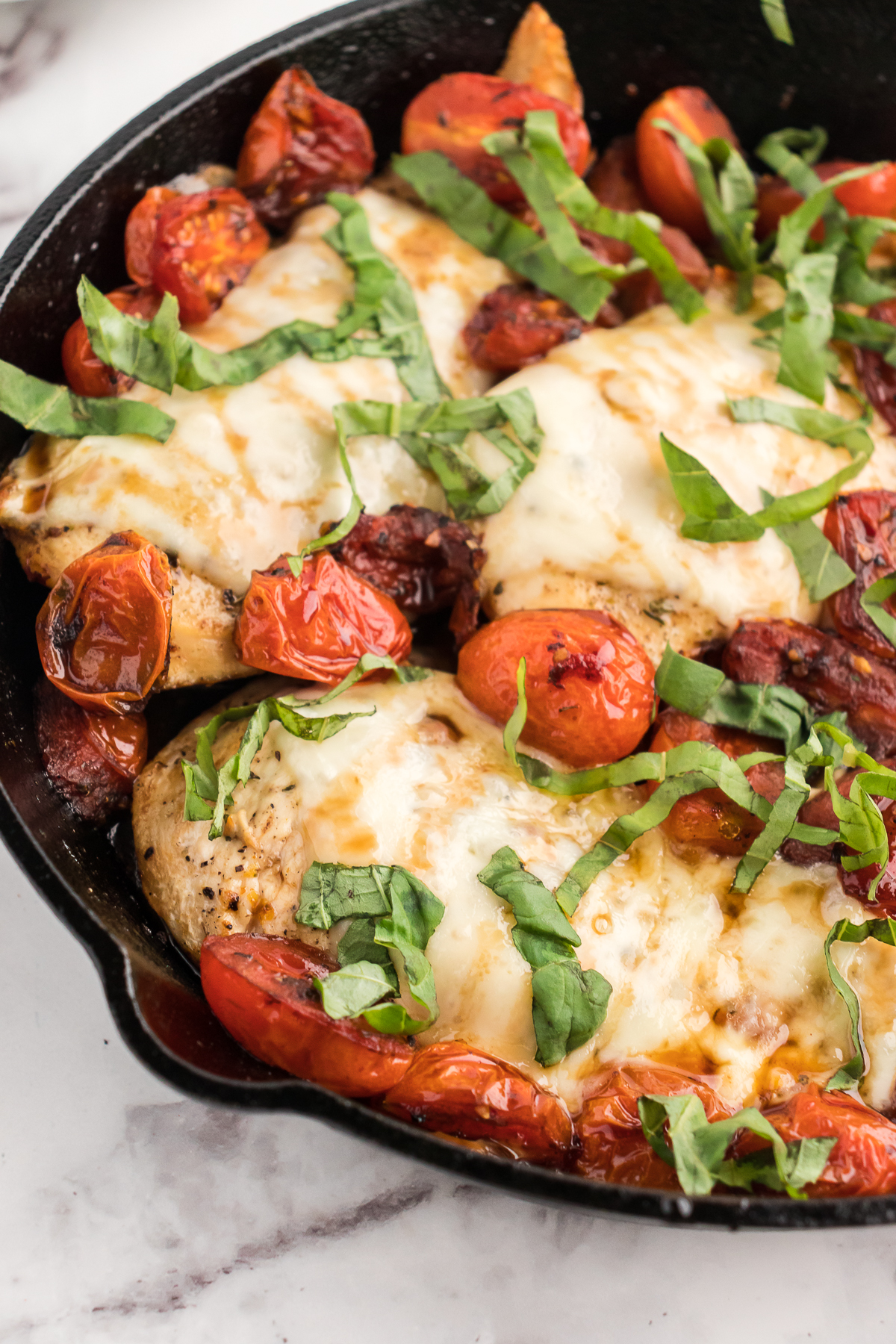 caprese chicken bake close up of the chicken cutlets with balsamic tomatoes and basil