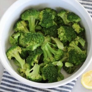 how to steam broccoli in the microwave, photo after cooking with lemon served on the side in a white dish