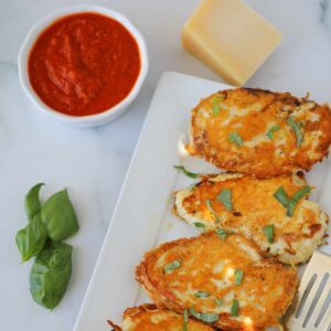 keto parmesan crusted chicken with sauce on a white plate