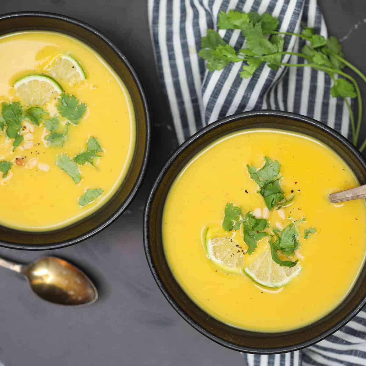 paleo butternut squash soup in a bowl with cilantro and limes