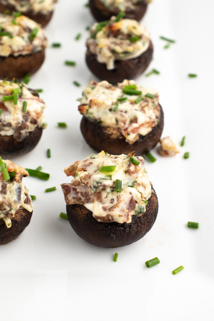 close up side angle of low carb stuffed mushrooms on a white platter
