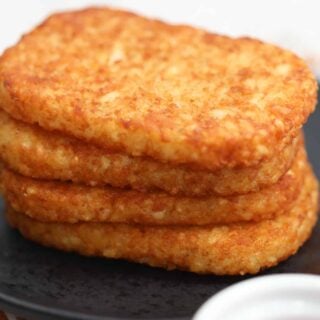 frozen hash browns in air fryer stacked on a black plate