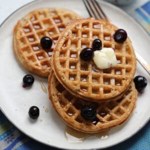 the frozen waffles in air fryer on a white plate with blueberries butter and syrup