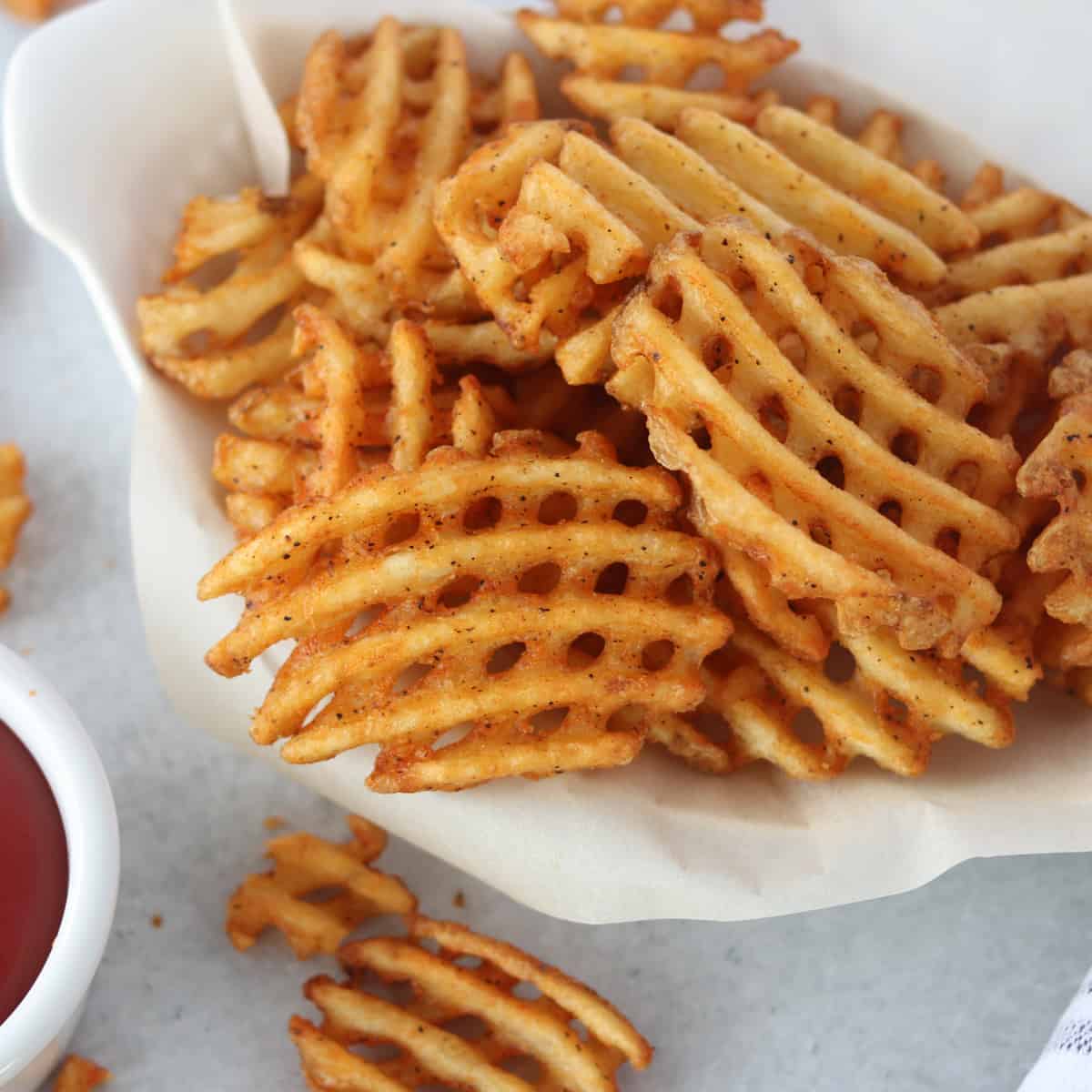 alexia air fryer frozen waffle fries in a white basket ready to eat