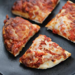 frozen pizza in air fryer cut into 4 on a black plate