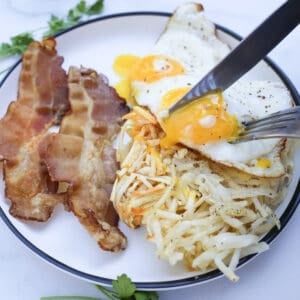 air fryer shredded hash browns on a plate with bacon and eggs