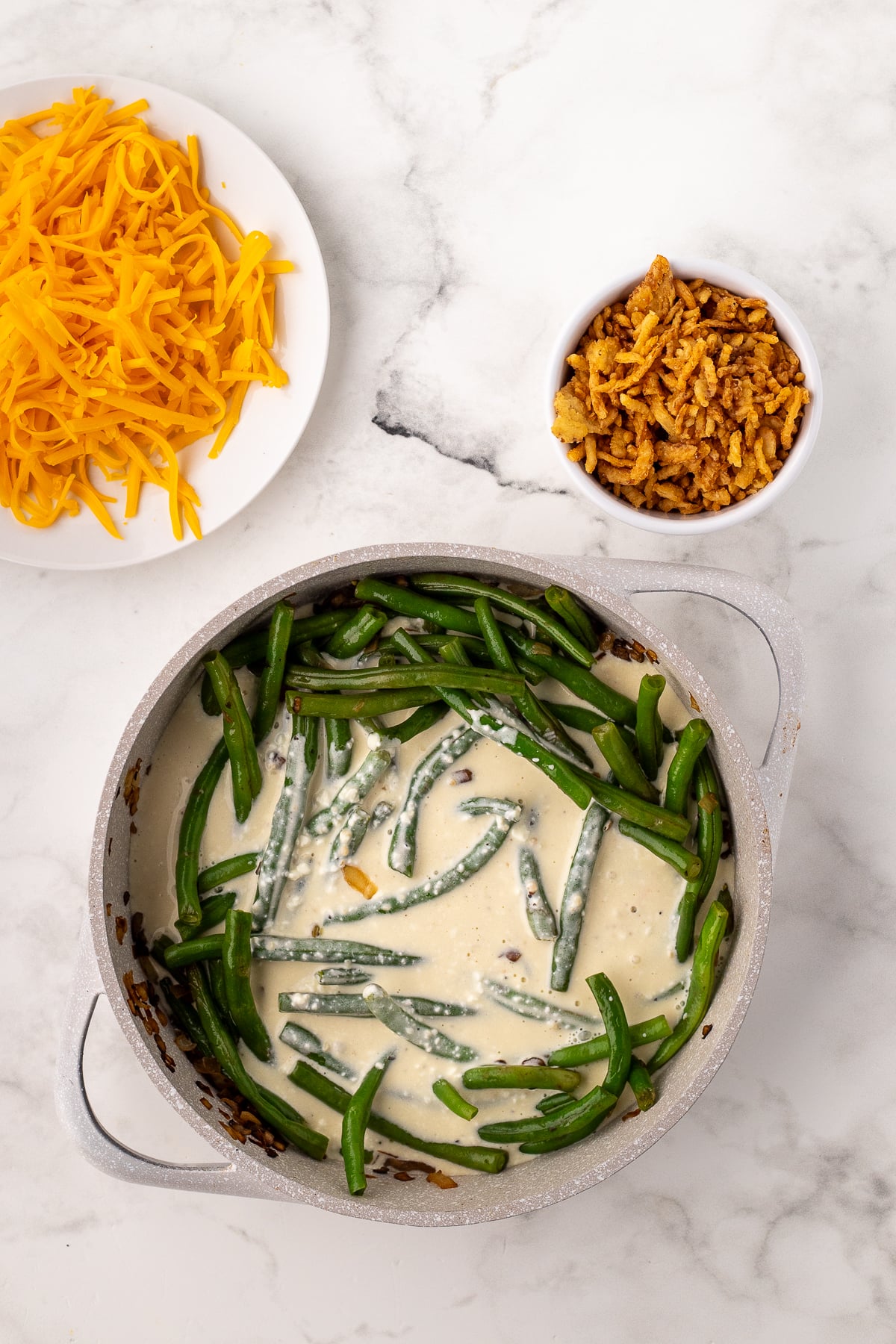 adding the cream cheese sauce to the skillet of green beans onions and mushrooms
