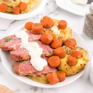 Plated corned beef and cabbage, served with potatoes, carrots and horseradish sauce.