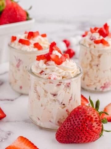 Three jars of keto cheesecake fluff topped with strawberries.