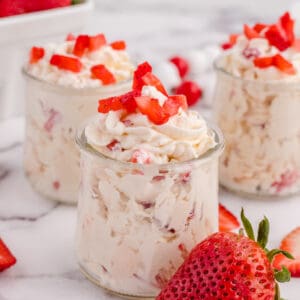 Three jars of keto cheesecake fluff topped with strawberries.