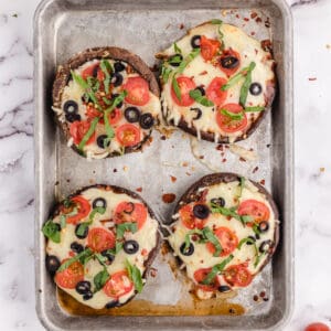 A sheet pan with four baked portobello mushroom caps.