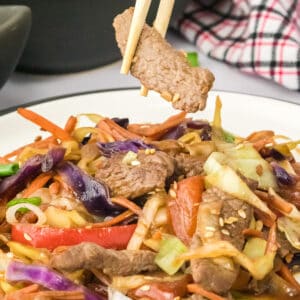 pepper steak stir fry being eaten with chop sticks.