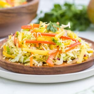 plated mango cabbage slaw on a wooden plate.