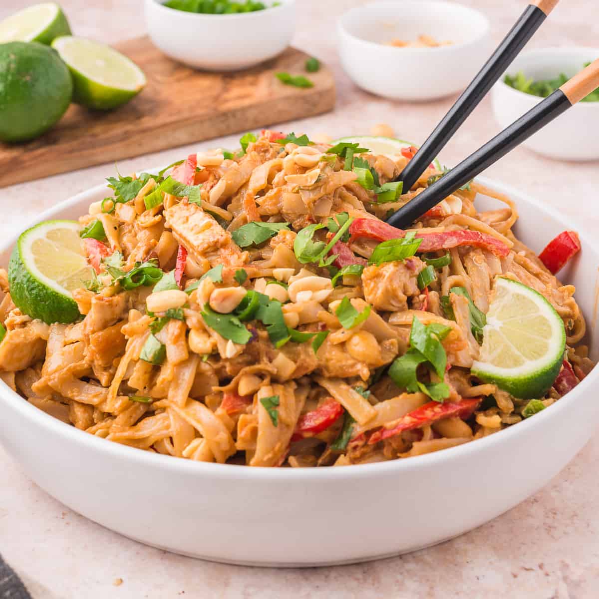 thai peanut noodles in a bowl on a pink background
