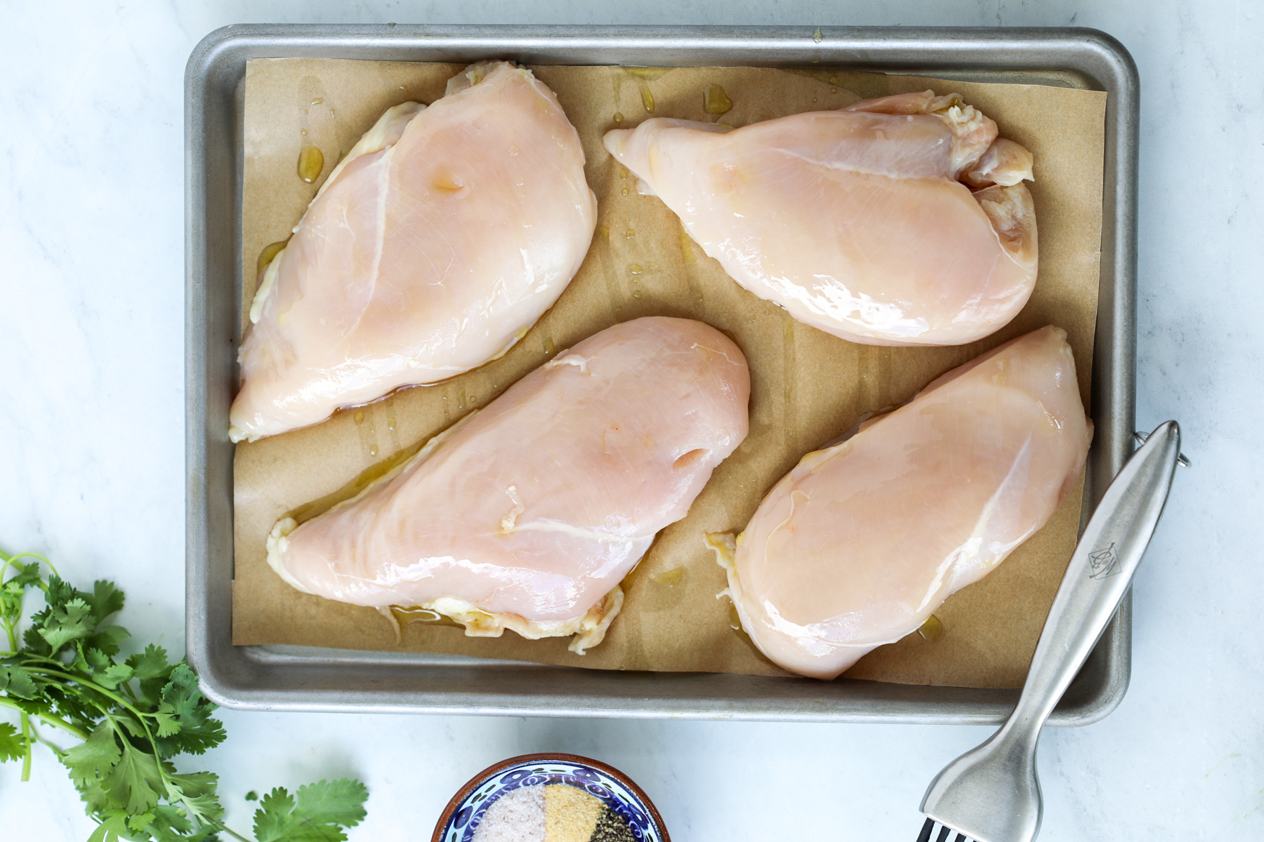 lay the boneless skinless chicken breasts on the parchment paper lined baking sheet before adding chicken rub