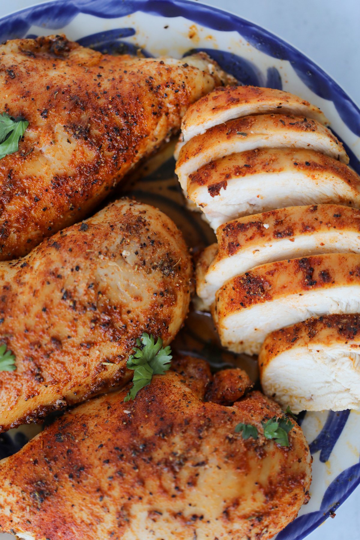 simple healthy baked chicken breasts out of the oven and sliced on a white and blue plate