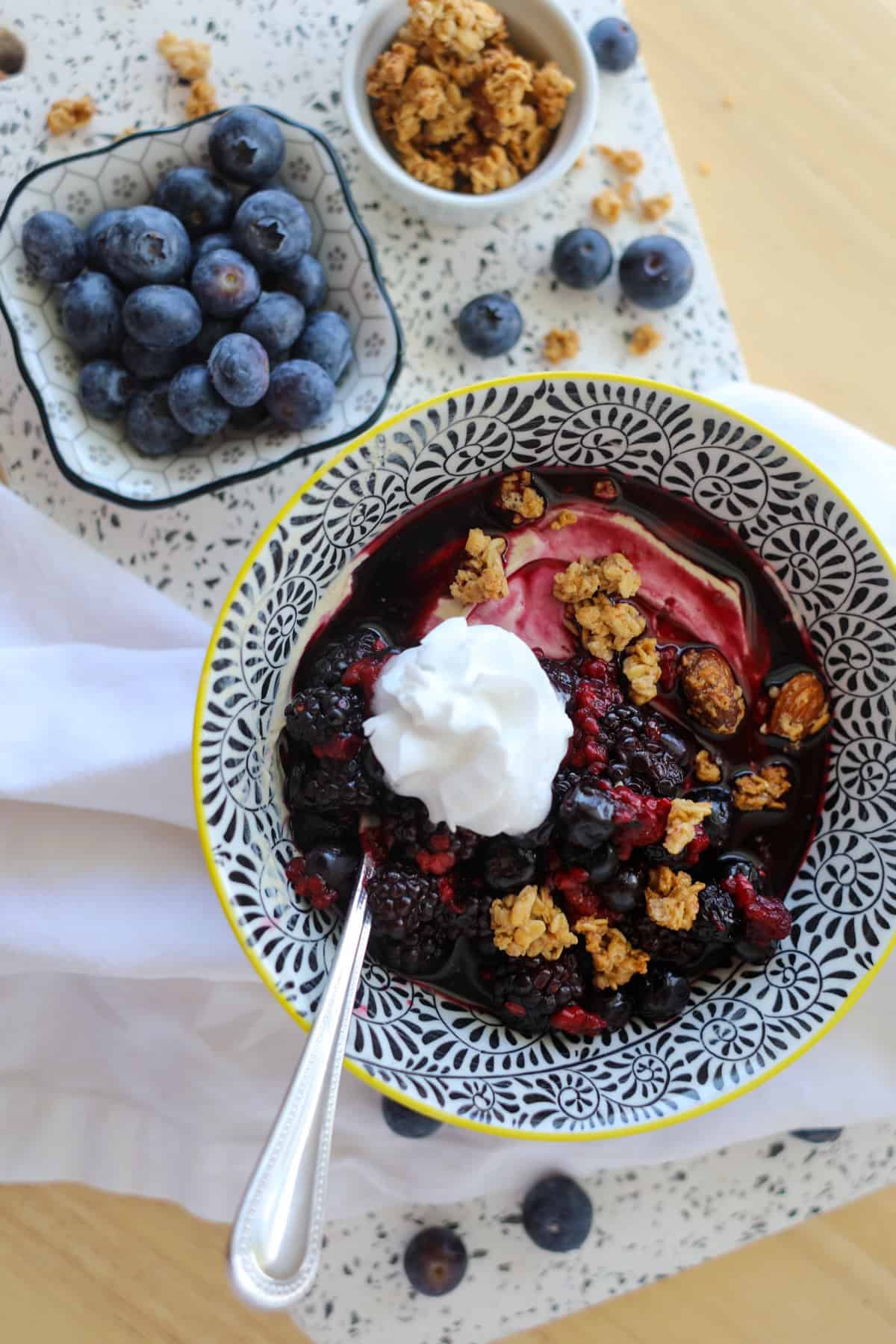 protein yogurt bowl ready to eat on a white cutting board with berries and granola on the side