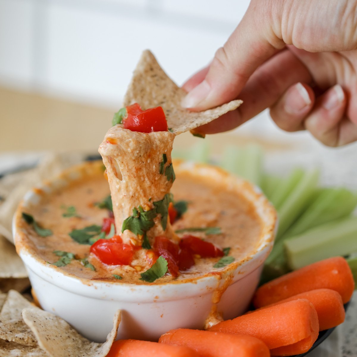 queso dip with cottage cheese in a white bowl with vegetable sticks