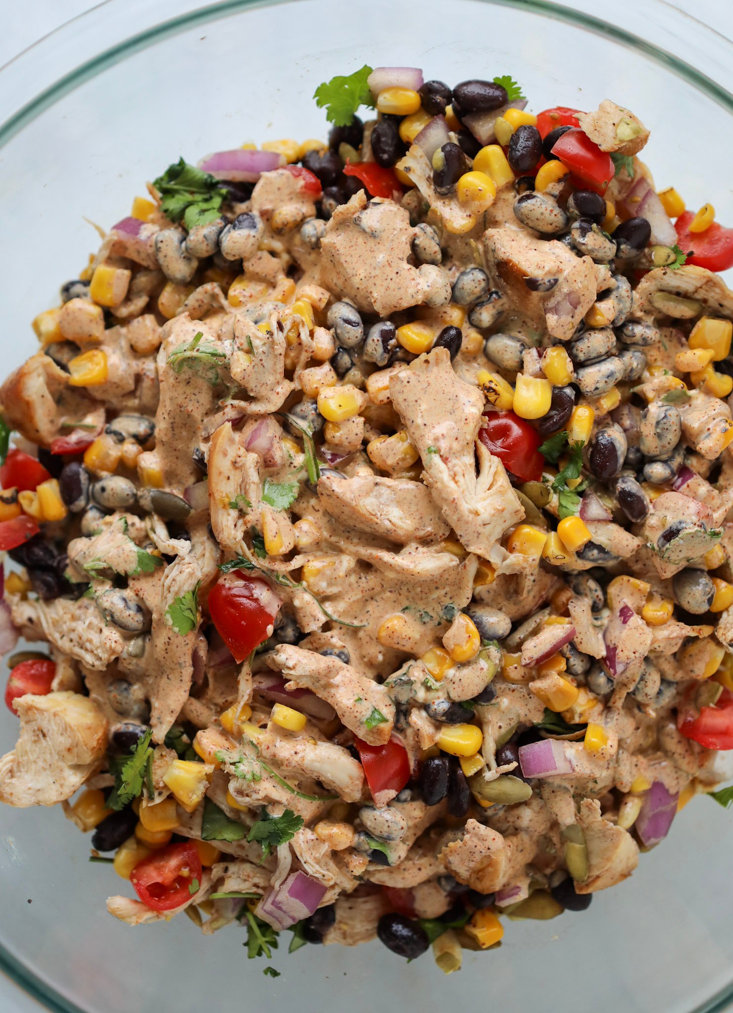pouring the dressing over the southwest salad with chicken