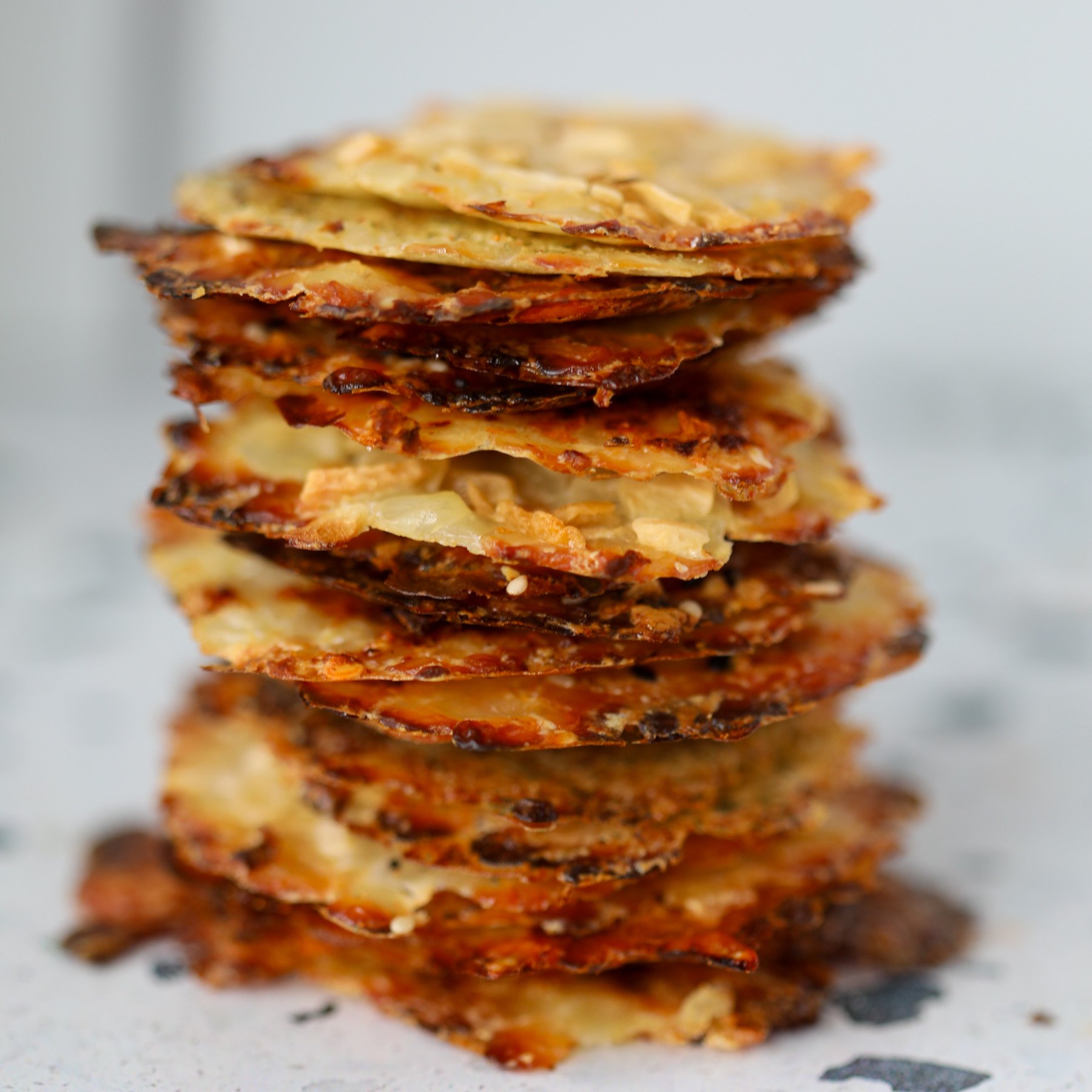 crispy cottage cheese chips stacked on a white plate