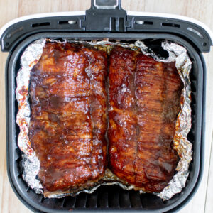 easy air fryer baby back ribs sprinkled with dry rub and brushed with bbq sauce