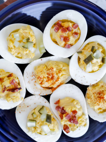 zero carb deviled eggs topped with bacon pickles and paprika on a blue plate