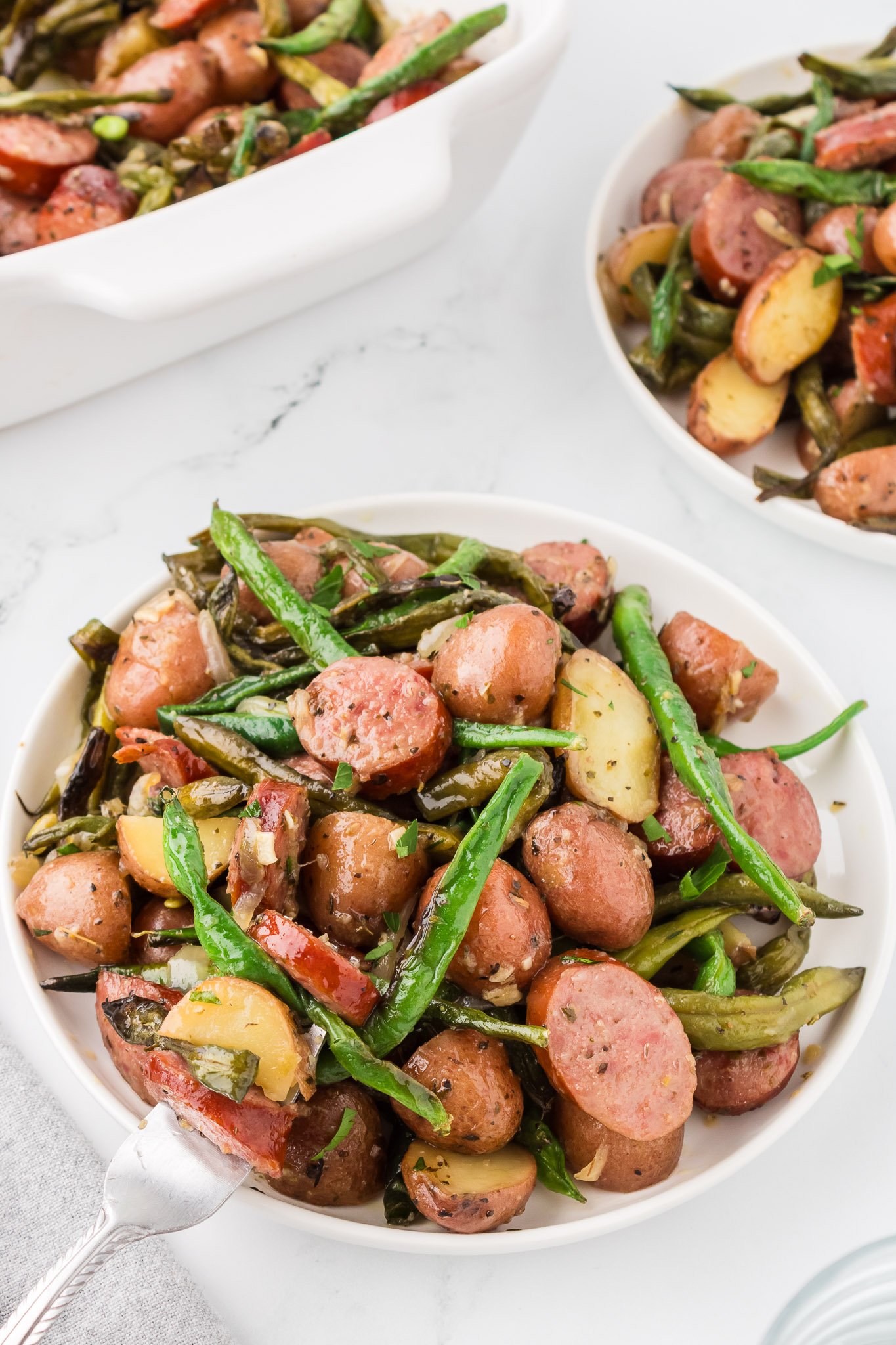 crock pot swamp potatoes in a white serving dish with kielbasa potatoes and green beans
