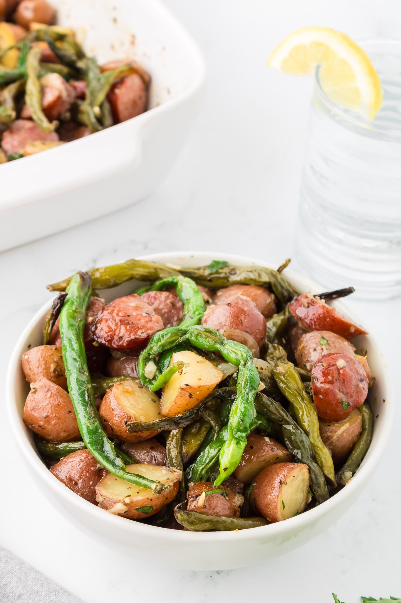 viral tiktok swamp potatoes in a crock pot with kielbasa sausage red potatoes and green beans in a white bowl before serving