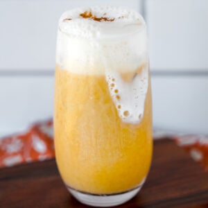 pumpkin smoothie with blended cottage cheese and whipped cream on a wooden cutting board