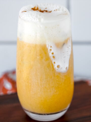 pumpkin smoothie with blended cottage cheese and whipped cream on a wooden cutting board