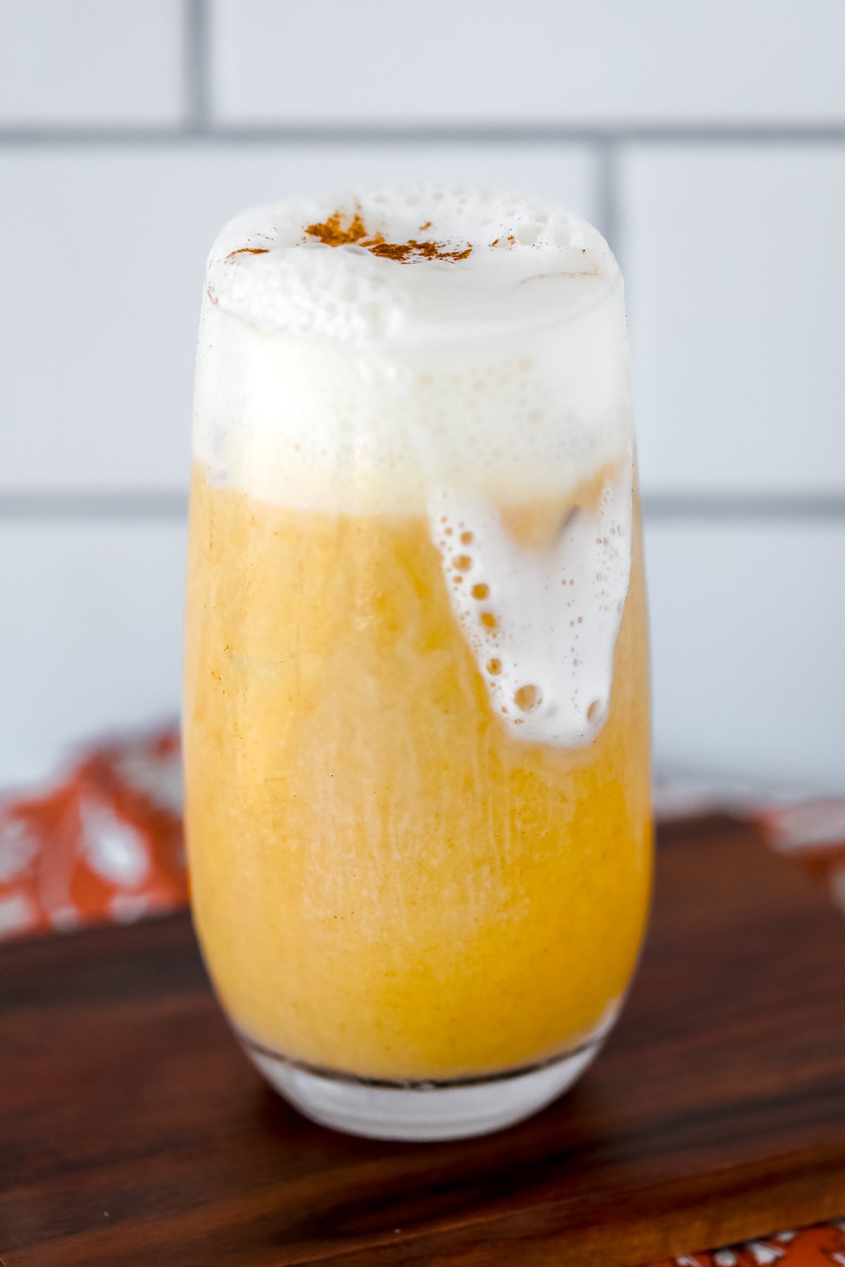 pumpkin protein smoothie topped with whipped cream and cinnamon on a cutting board