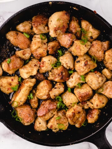 cooked honey garlic chicken cubes in a cast iron skillet
