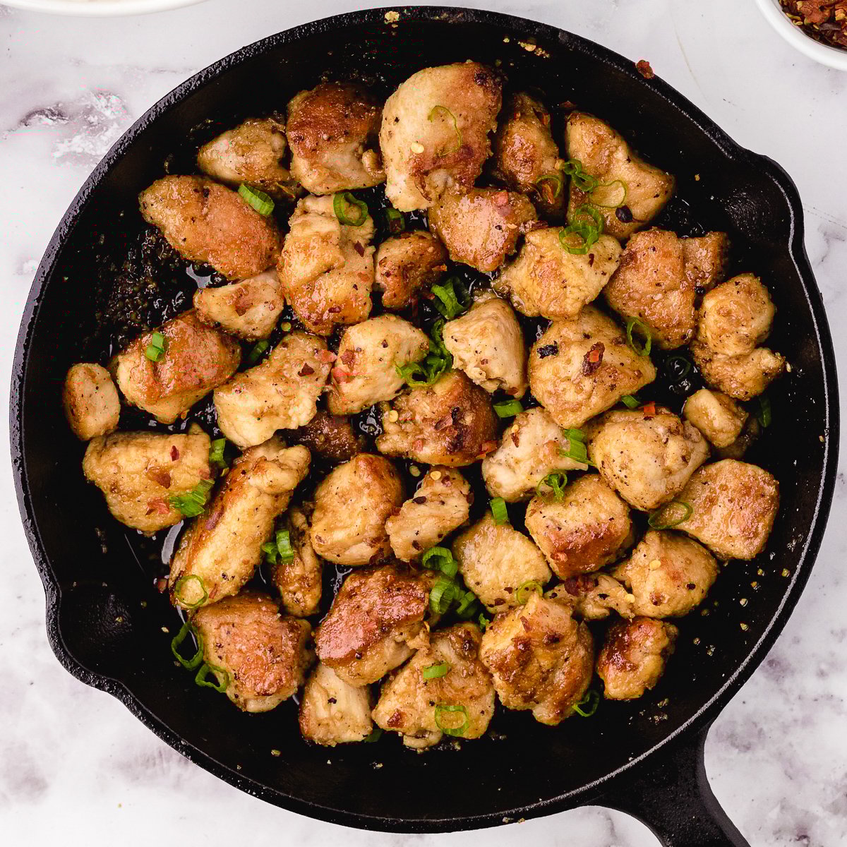 cooked honey garlic chicken cubes in a cast iron skillet