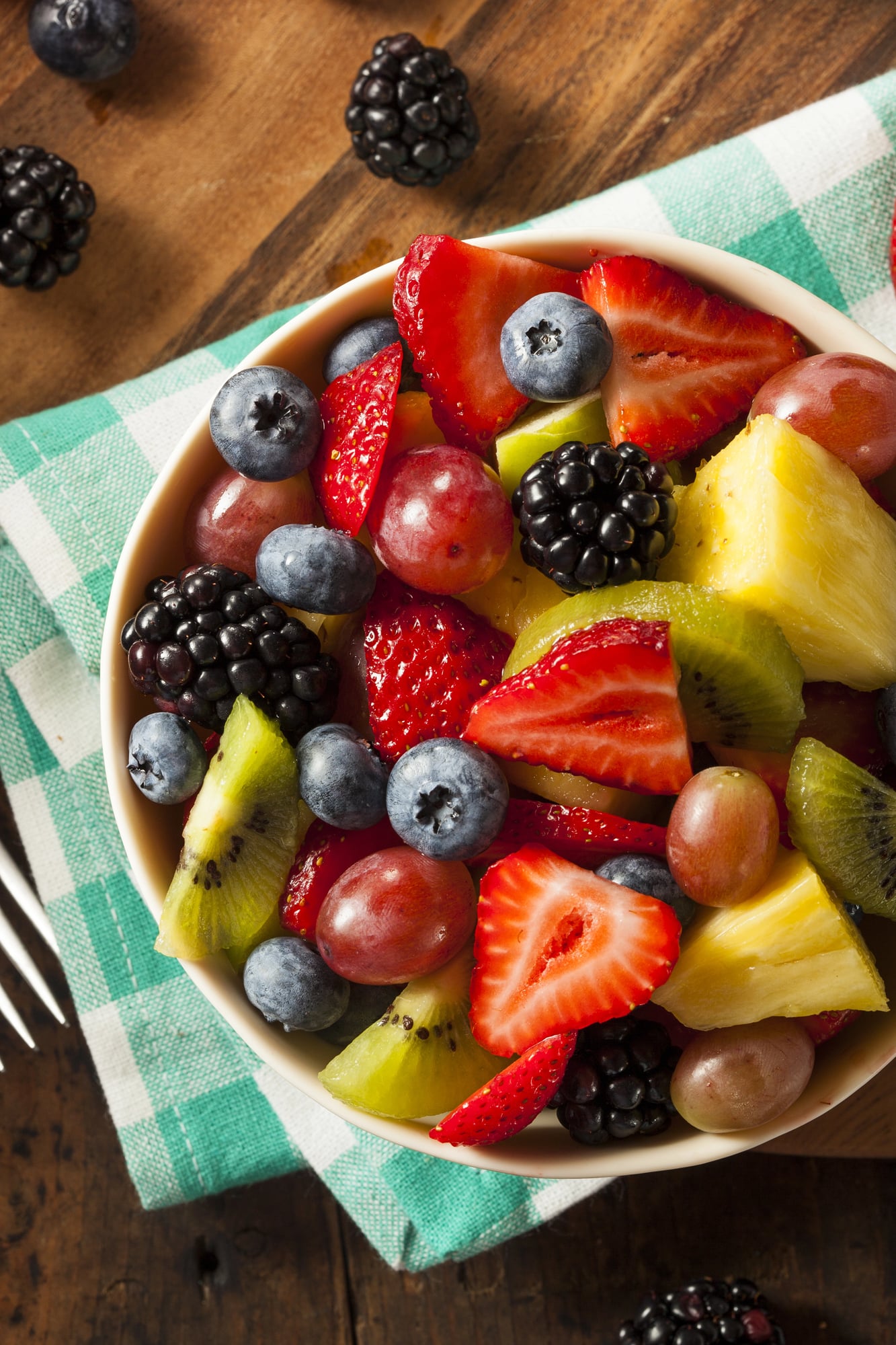 fruit salad in a white bowl on a green checked napkin