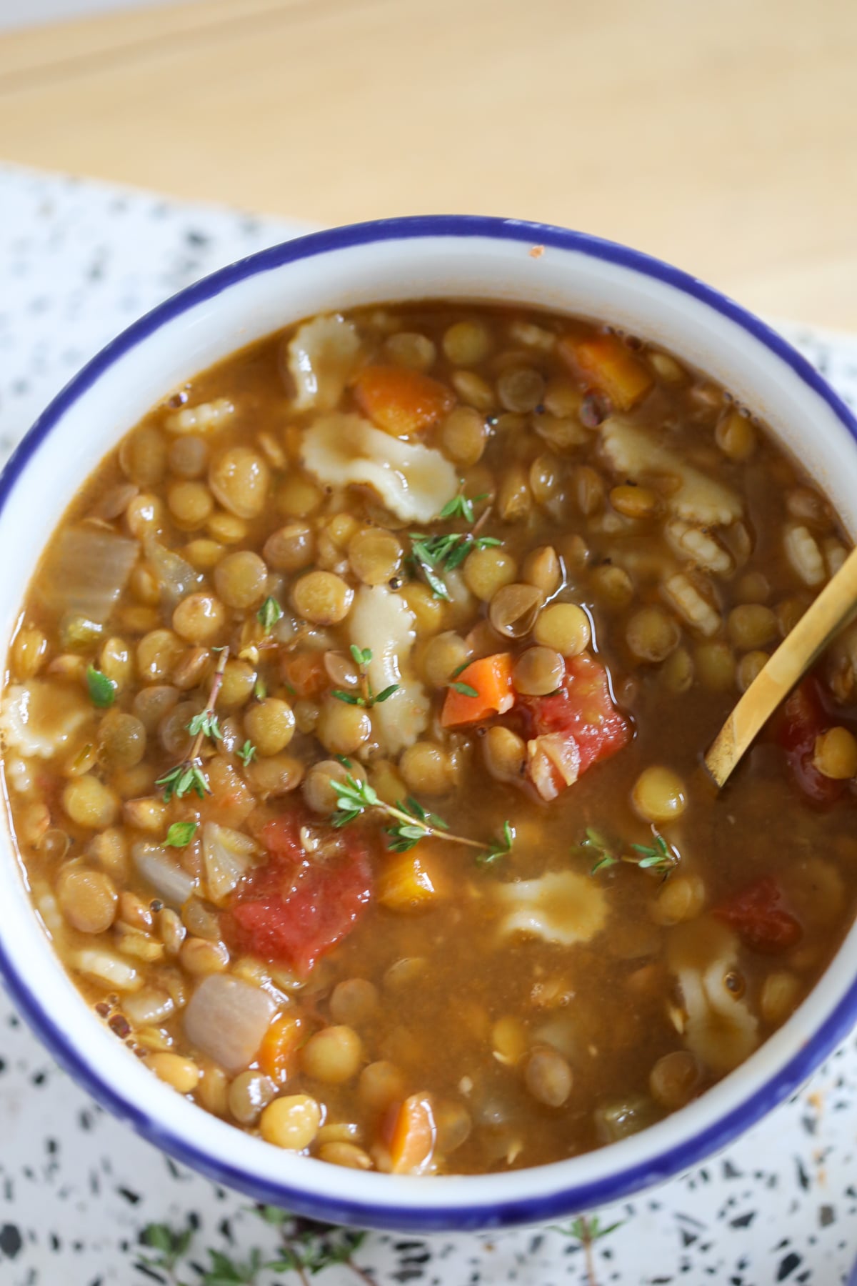 Closeup image of high protein lentil soup served in a white bowl with a blue rim.