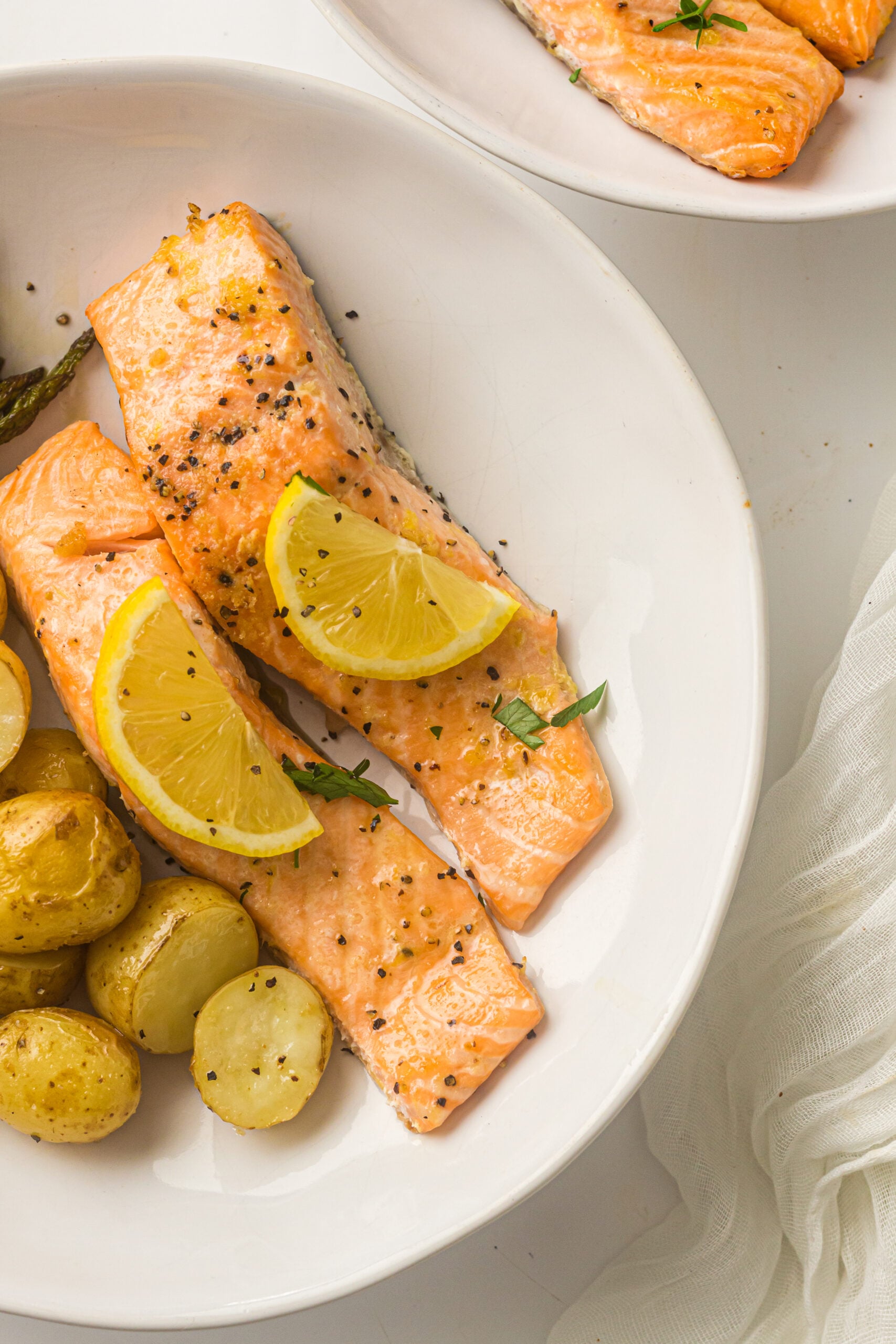 two pieces of salmon with  baby potatoes on a white plate